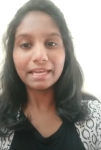 A woman with long, dark hair is speaking directly to the camera. She is wearing a black top with a white, patterned outer garment and is set against a plain, light-colored background. With determination in her eyes, she shares her entrepreneurial dreams for MediTruck and its potential impact on healthcare.