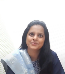 A woman with long dark hair, identified as Rakhi Jain, is seated and looking slightly to the left. She is wearing a dark blue top and a light blue scarf adorned with intricate designs. The background is plain white with a light polka dot pattern on the left side, reflecting the strong foundation of the InFED-NEN IGNITE Program.