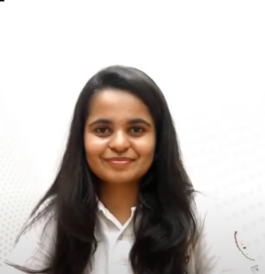 A person with long dark hair, likely Rutuja Sahane, is smiling at the camera. They are wearing a white top and standing against a light background, reflecting the confidence gained from the InFED-NEN IGNITE Program that honed their entrepreneurial skills.