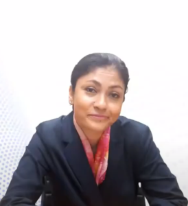 Smriti Chaudhry, with dark hair pulled back, is wearing a navy blue suit and a colorful scarf. She is sitting and looking forward against a plain light background, ready to share her insights from the InFED-NEN IGNITE Program's intensive course.
