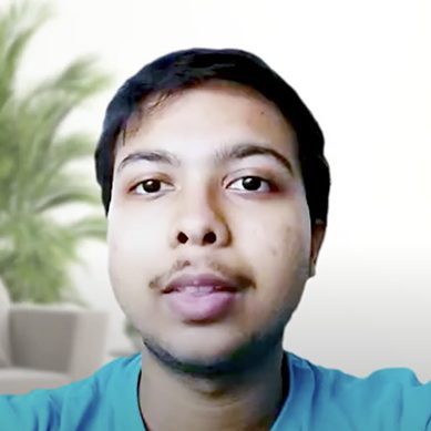 Hombre joven, Akshay R Morab, con camisa azul y expresión neutra, en interior con fondo difuminado con vegetación.