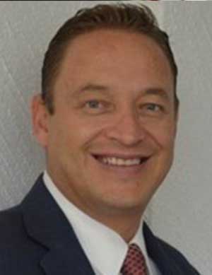 A smiling man in a suit with a tie, representing EmpowerED México's commitment to education in 2024.