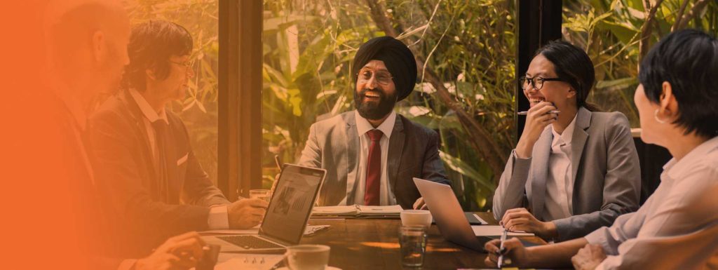 Un equipo de diversos profesionales se enzarza en un debate reflexivo durante una reunión de despegue en un moderno espacio de oficinas con vegetación.