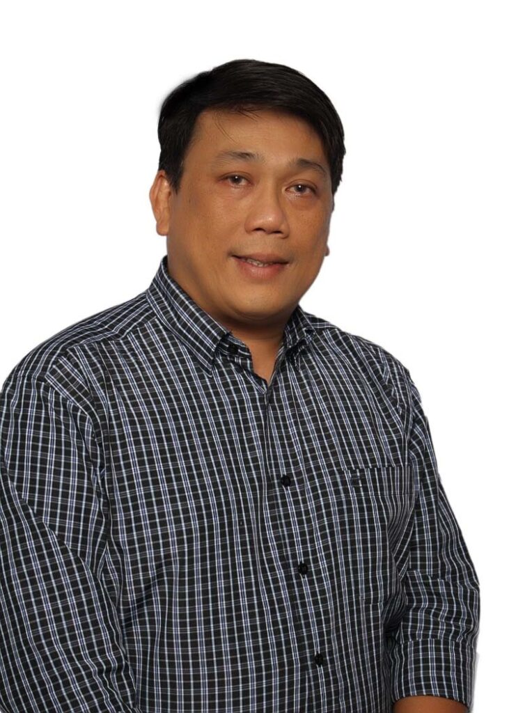 A portrait of a middle-aged man wearing a blue checkered shirt, smiling slightly against a plain white background.